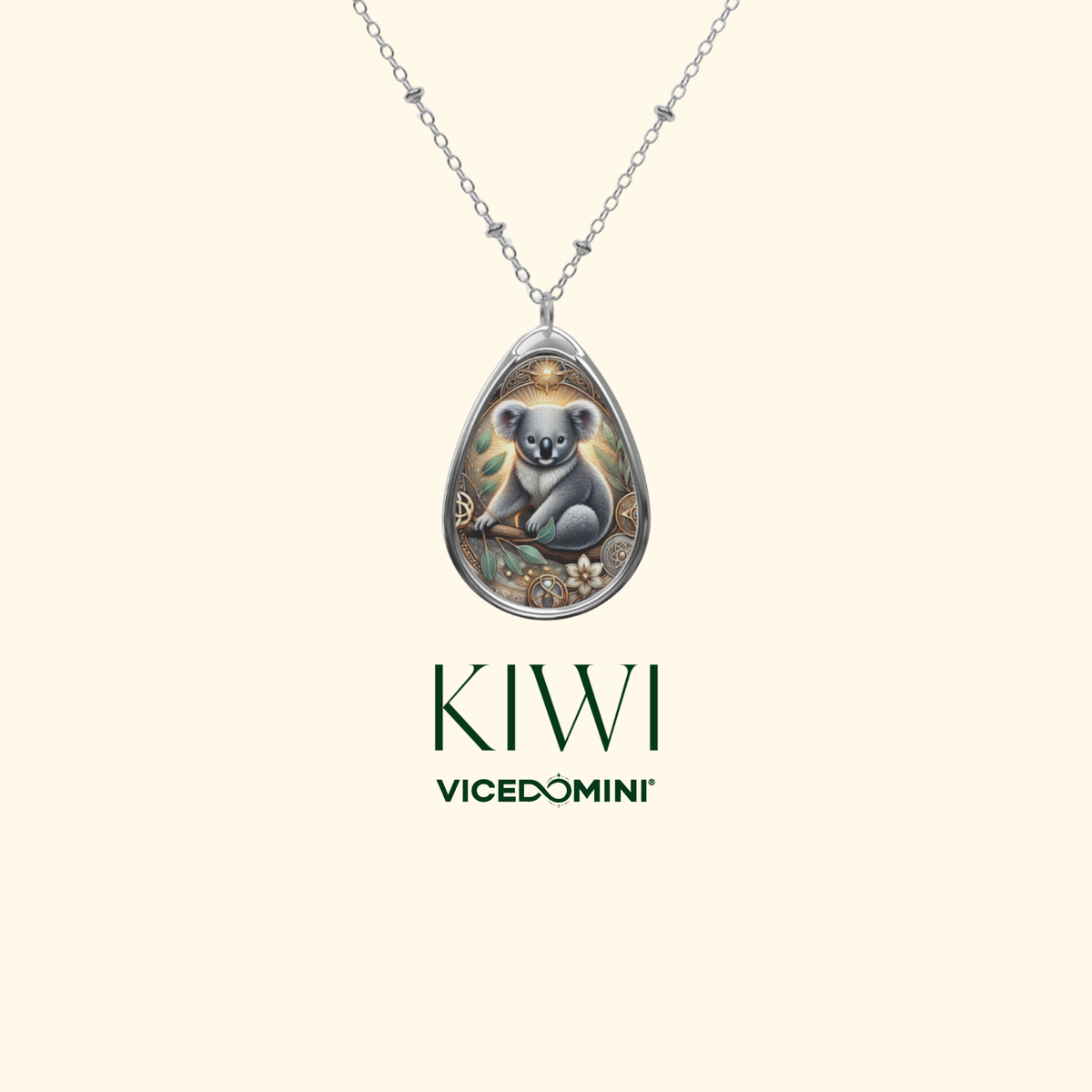A silver teardrop pendant necklace featuring an illustrated koala and floral design, shown on a light cream background with the brand name 'KIWI VICEDOMINI' printed below.