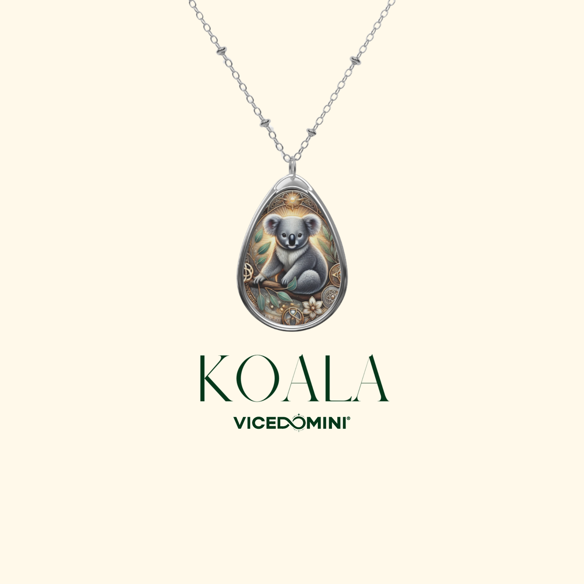 A silver teardrop pendant necklace featuring an illustrated koala on a branch, shown against a light cream background with the text 'KOALA VICEDOMINI' below.