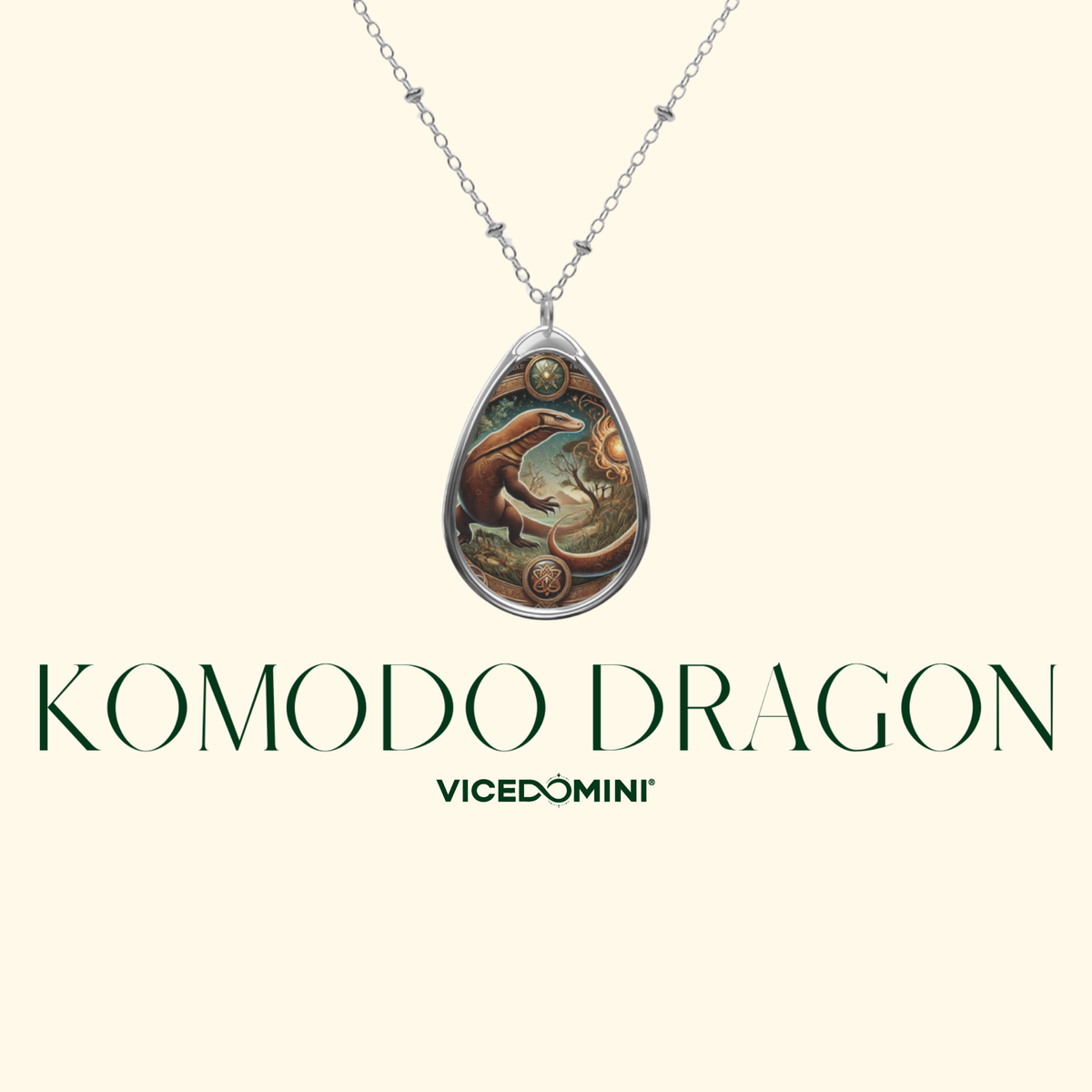 Silver-toned necklace with a teardrop pendant featuring an illustrated dragon design, shown on a cream background with the text 'KOMODO DRAGON' and 'VICEDOMINI'.