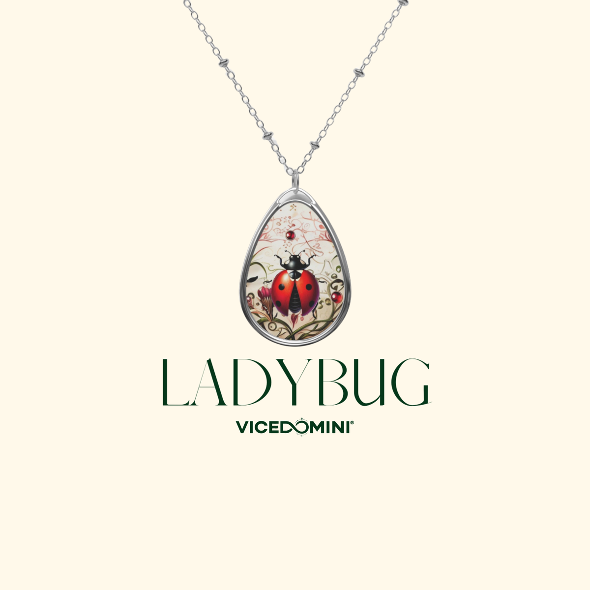 A teardrop-shaped pendant necklace featuring a ladybug illustration on a cream background with a silver chain, shown against a light cream backdrop with the brand text 'LADYBUG' and 'VICEDOMINI' below.