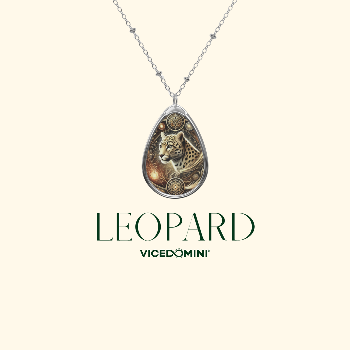 A teardrop-shaped silver pendant necklace featuring an engraved leopard design with gold and brown accents, suspended from a silver chain on a light cream background. The text 'LEOPARD' and 'VICEDOMINI' is printed below the necklace.