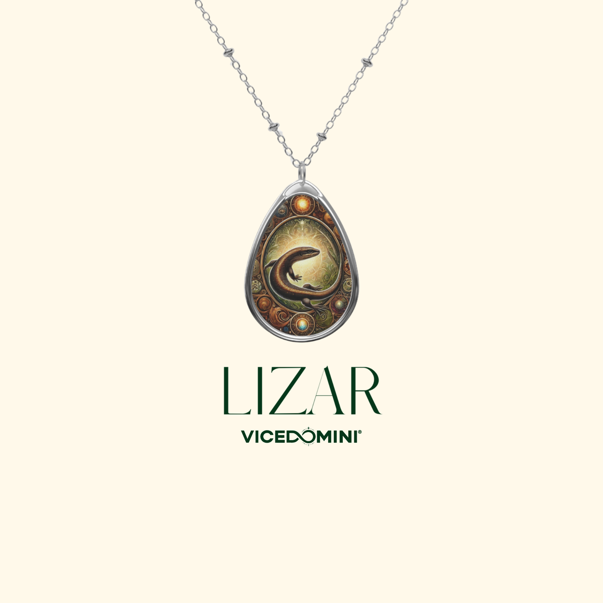 A silver teardrop pendant necklace featuring a detailed fantasy illustration of a dark dragon coiled within a golden circular frame, set against a light cream background with the brand name 'LIZAR VICEDOMINI' printed below.