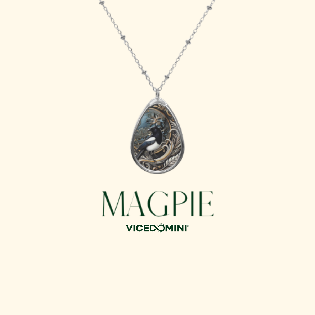 A teardrop-shaped pendant necklace with a silver-toned chain, featuring an illustrated magpie design. The brand name 'MAGPIE' and 'VICEDOMINI' are displayed below the necklace on a solid cream-colored background.