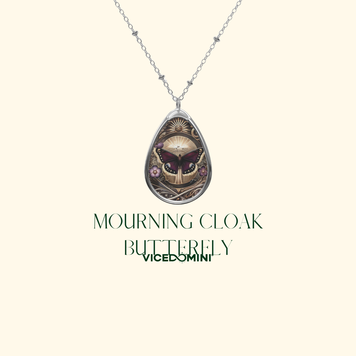 A silver teardrop pendant necklace featuring an intricate butterfly and cloak design, displayed on a cream background with the text 'MOURNING CLOAK BUTTERFLY VICEDOMINI'.
