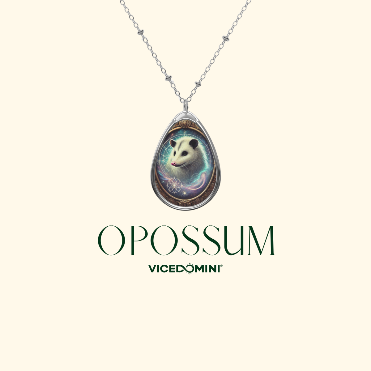 A Vicedomini Opossum pendant necklace on a silver chain, featuring a teardrop-shaped pendant with a detailed illustration of an opossum in a mystical blue and purple environment. The brand name 'OPOSSUM VICEDOMINI' is printed below the necklace on a solid cream background.