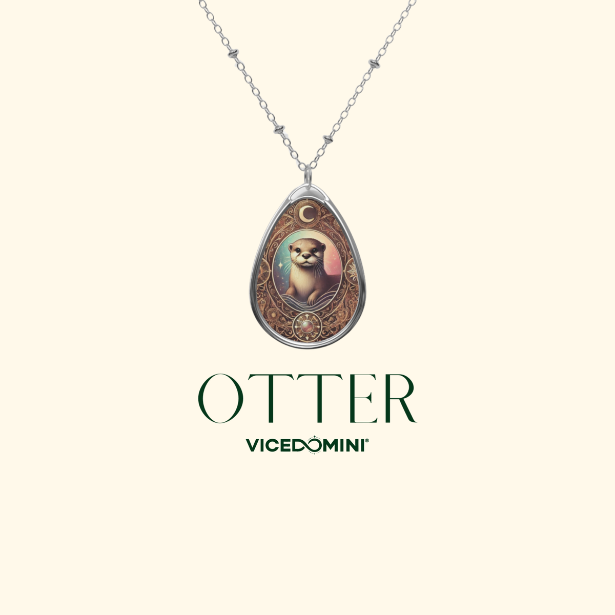 A silver-toned teardrop pendant necklace featuring an illustrated otter portrait with ornate gold and brown detailing, shown on a light cream background with the text 'OTTER VICEDOMINI' below.