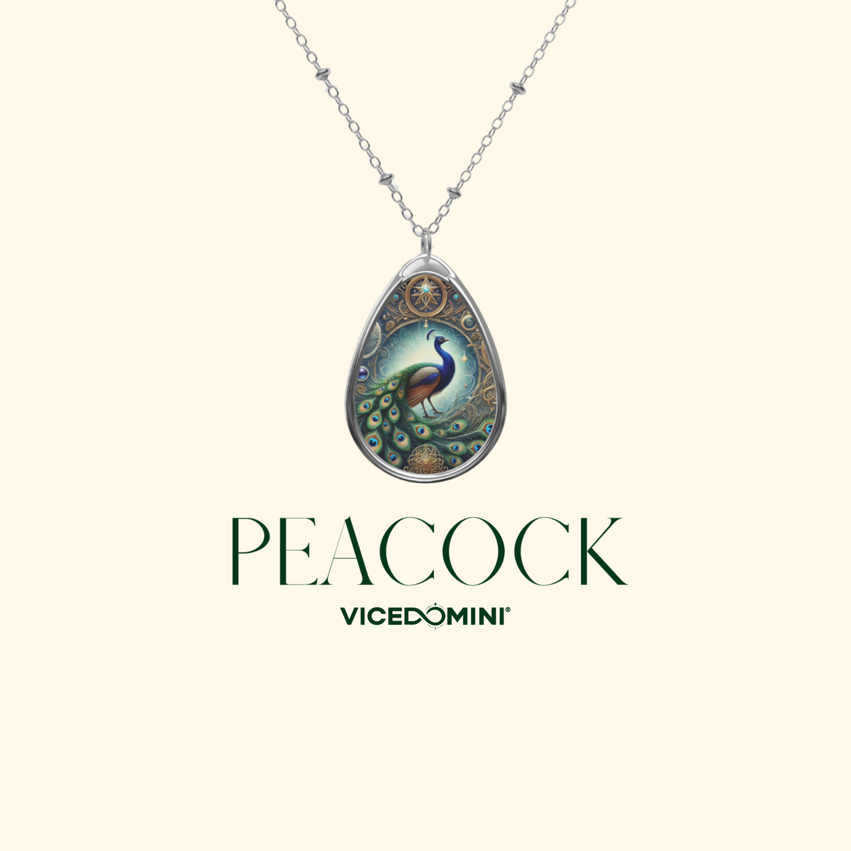 A Vicedomini necklace with a teardrop-shaped pendant featuring a detailed peacock illustration, shown against a light cream background with the brand name 'Vicedomini' and the word 'PEACOCK' printed below.