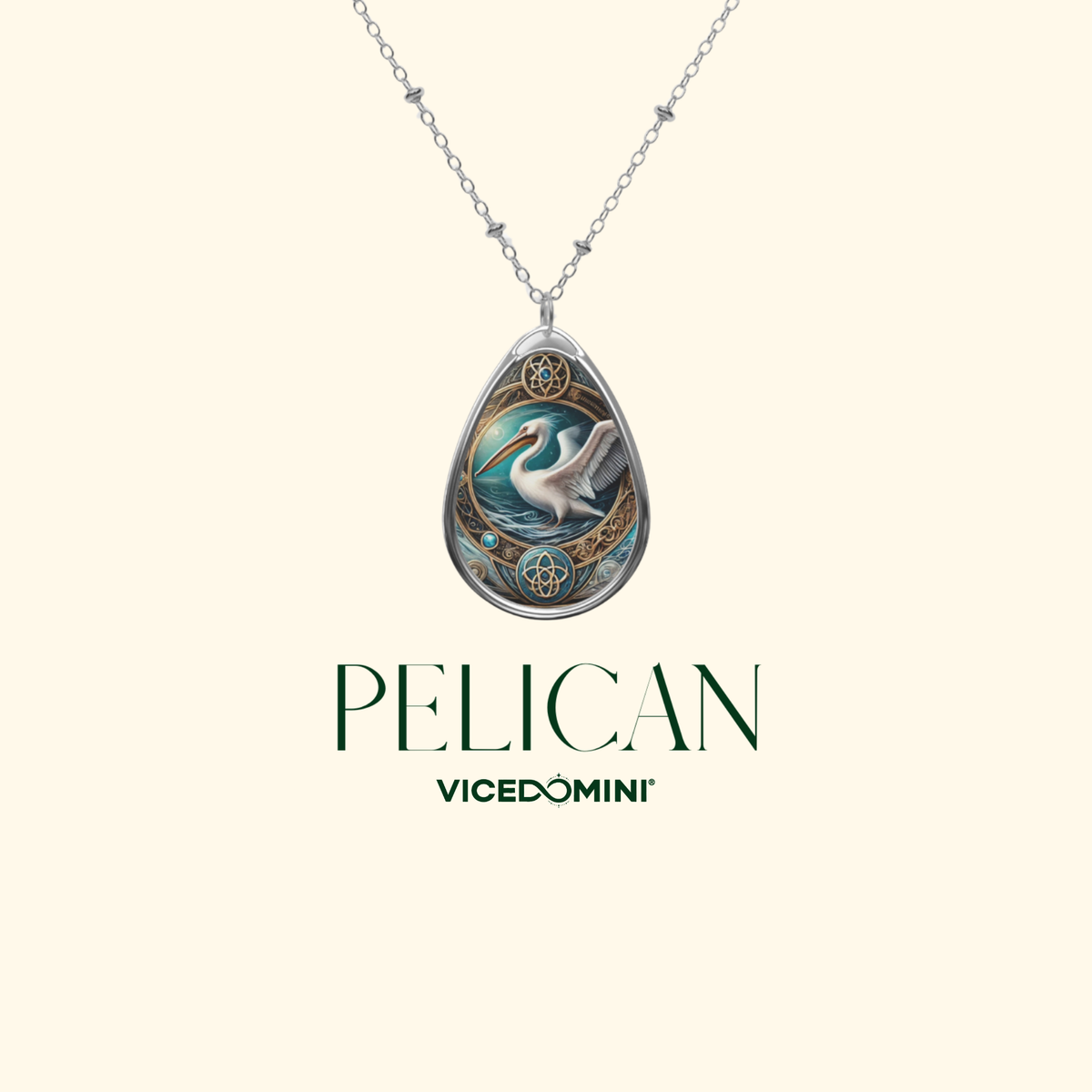 A silver-toned teardrop pendant necklace featuring an illustrated white pelican in a blue and teal landscape with gold circular details, shown on a light cream background with the text 'PELICAN VICEDOMINI' below.