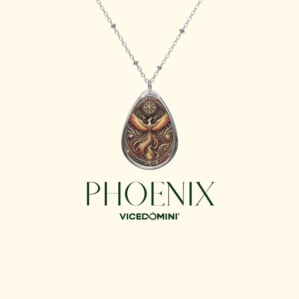 A silver teardrop pendant necklace featuring an intricate phoenix design with warm orange, gold, and brown tones, displayed on a cream background with the text 'PHOENIX VICEDOMINI' below.