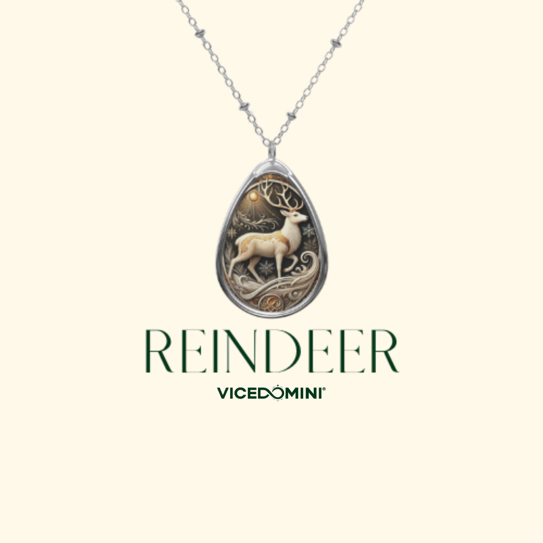 A silver teardrop pendant necklace featuring an intricate engraved deer design, displayed on a light cream background with the brand name 'VICEDOMINI' and the word 'REINDEER' printed below.
