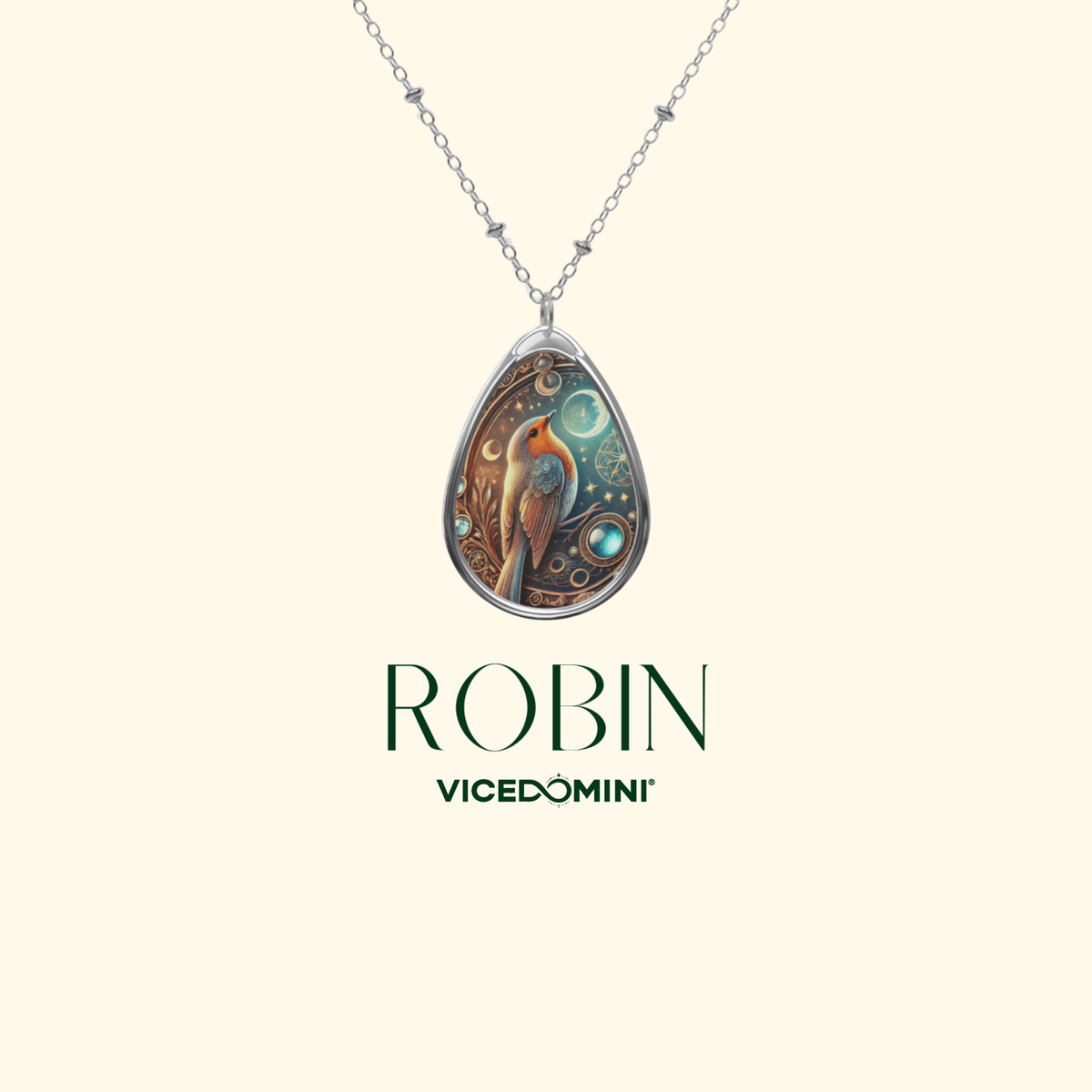 A robin necklace pendant displayed against a light beige background. The pendant showcases a detailed robin illustration with celestial elements, accompanied by the text "ROBIN" and "VICEDOMINI" in elegant typography.