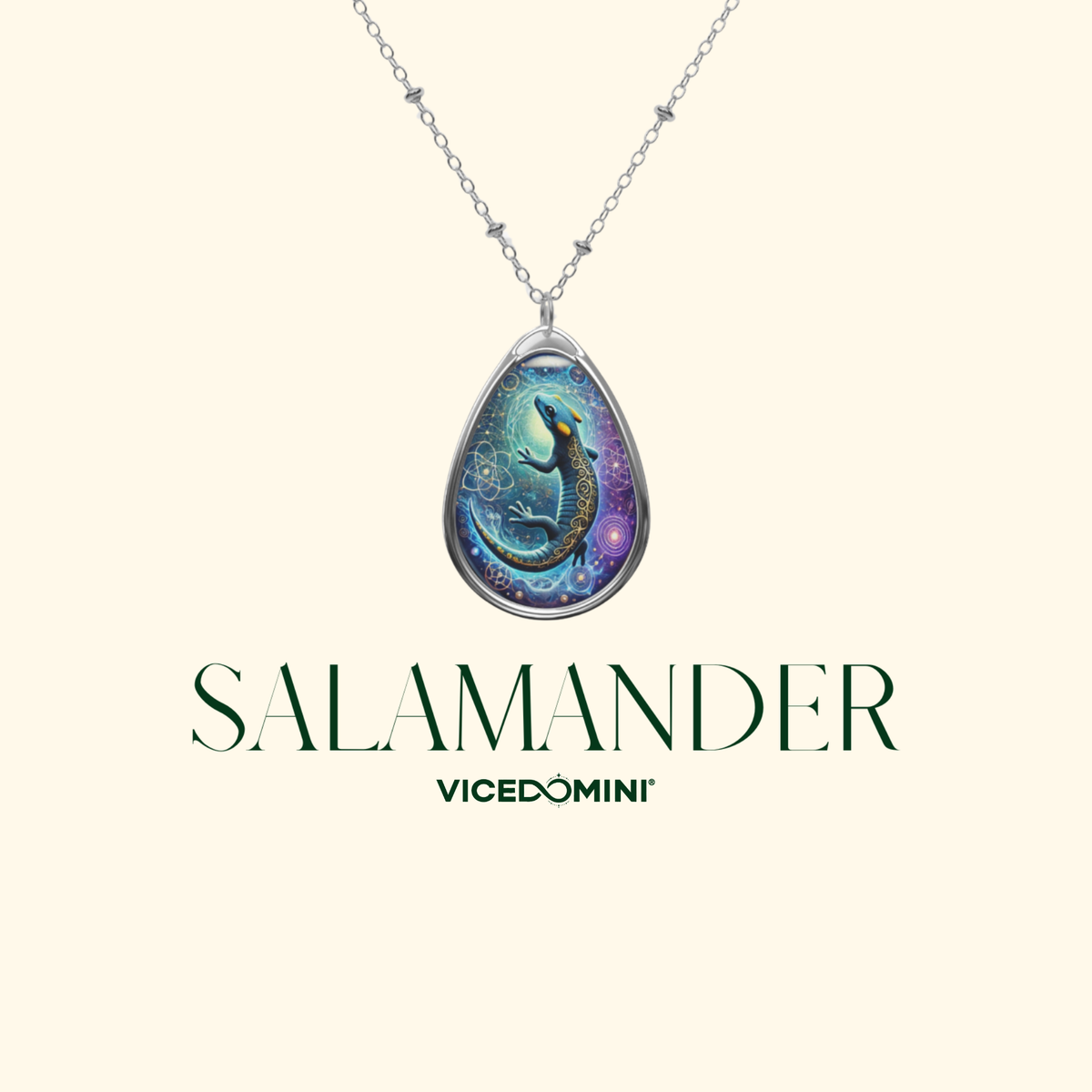 A close-up of a teardrop pendant necklace featuring a luminous blue and black salamander with cosmic and geometric details. The chain has delicate metalwork, and "SALAMANDER" and "VICEDOMINI" are written in elegant typography.