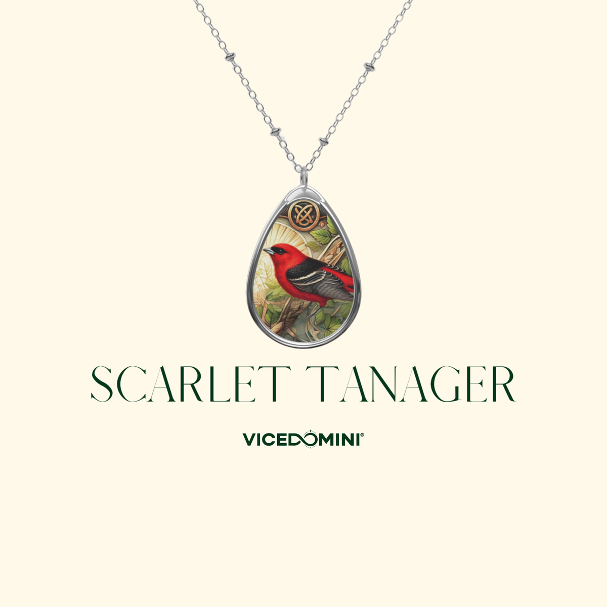 A teardrop-shaped pendant necklace featuring a detailed illustration of a scarlet tanager bird, suspended from a silver chain. The pendant is displayed against a light cream background with the text 'SCARLET TANAGER' and the brand 'VICEDOMINI' printed below.