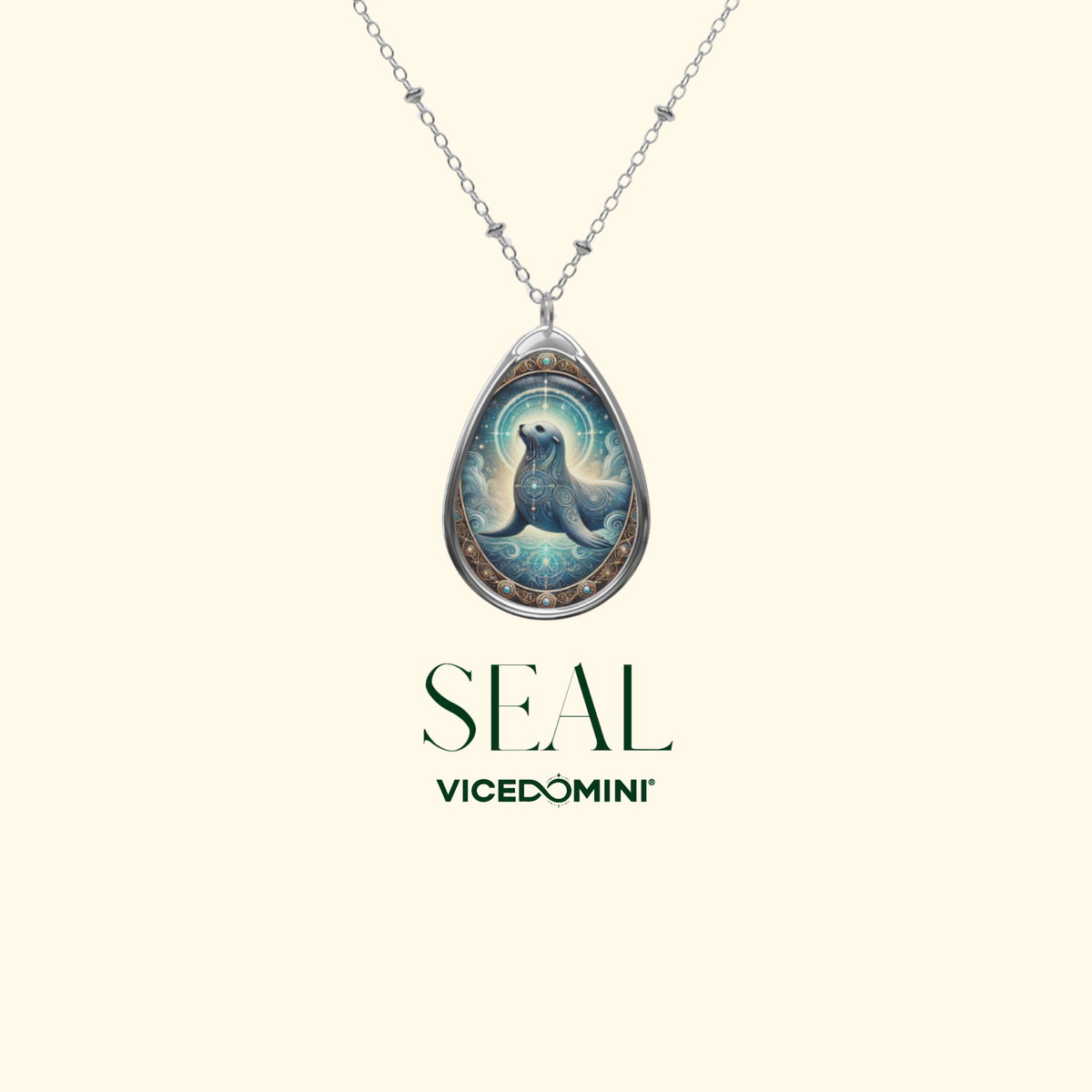 A delicate silver chain holds a teardrop-shaped pendant with an elegant seal design, set against a cream background. The pendant features a celestial-style illustration of a seal with intricate swirls and glowing elements. The text "SEAL" and "VICEDOMINI" appears below the necklace.