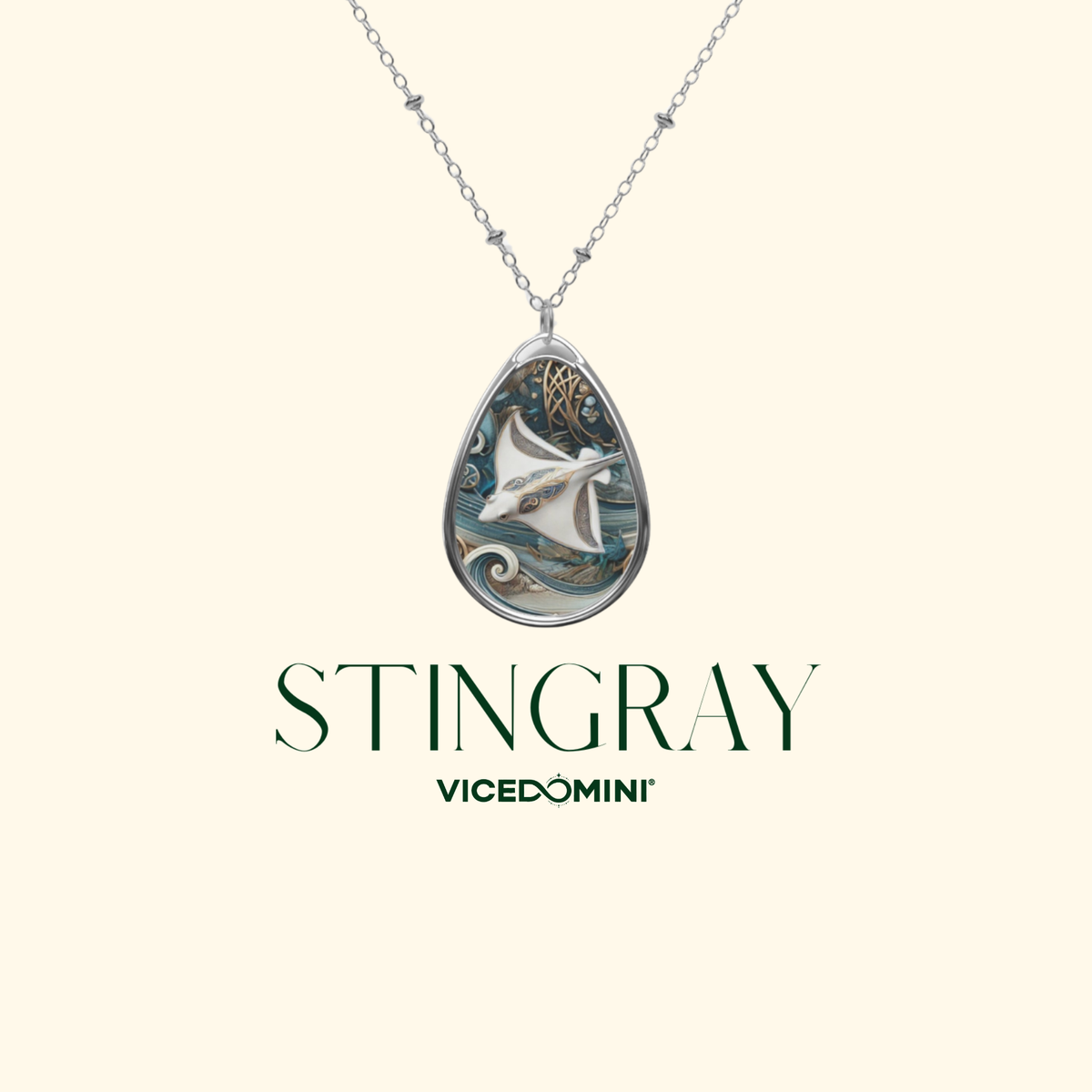 A teardrop-shaped pendant necklace featuring a detailed illustration of a white-streaked stingray over blue-green water, suspended from a silver chain. The brand name 'VICEDOMINI' and the word 'STINGRAY' are printed below the pendant on a solid pale cream background.