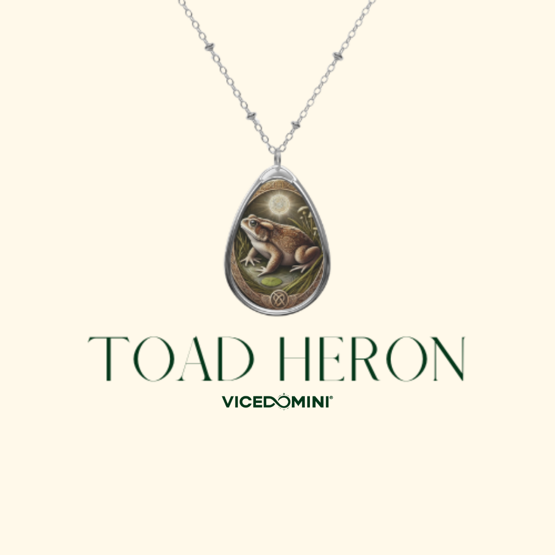A silver teardrop pendant necklace featuring an illustration of a toad and a full moon, displayed on a cream background with the text 'TOAD HERON' and 'VICEDOMINI' underneath.