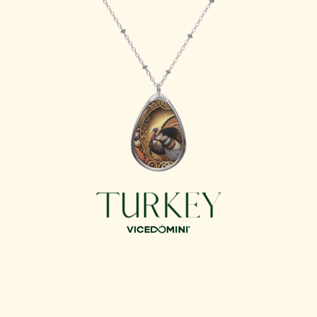 A silver-toned teardrop pendant necklace featuring an illustrated wild turkey design, shown against a light cream background with the text 'TURKEY' and 'VICEDOMINI' below.
