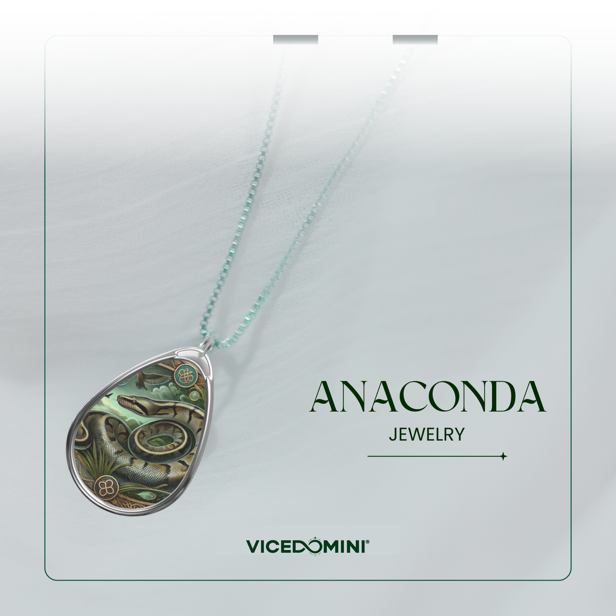 A teardrop-shaped pendant necklace with a detailed green and brown snake illustration inside a silver frame, hanging from a light mint-green chain. The pendant is displayed on a white card labeled 'ANACONDA JEWELRY' and 'VICEDOMINI'.