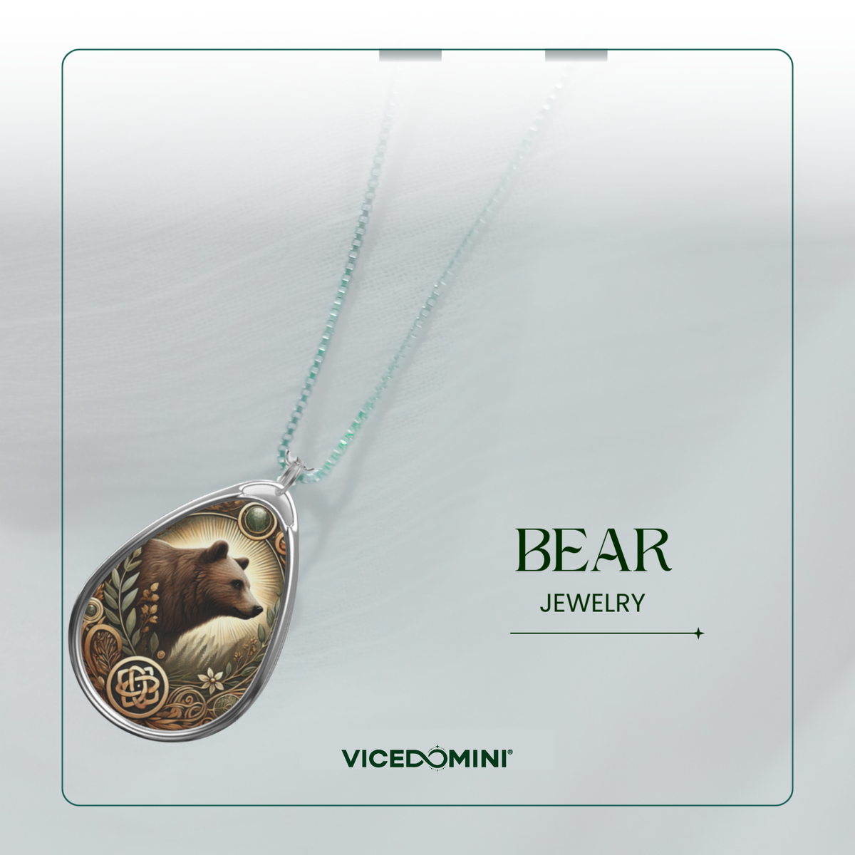A teardrop-shaped pendant necklace from Vicedomini, featuring an engraved bear illustration with Celtic knot details and a light blue chain, displayed on a clean white background with text reading 'BEAR JEWELRY'.