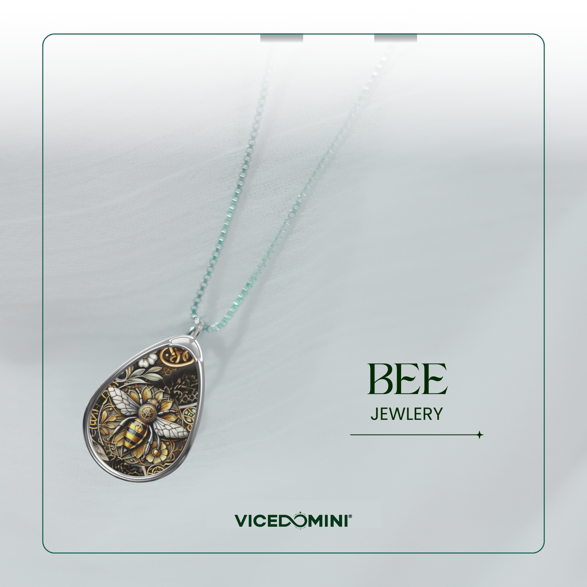 A teardrop-shaped pendant necklace from Vicedomini Bee Jewellery, featuring a detailed gold and silver bee design on a silver-toned background, suspended from a delicate mint green chain against a light gray background.