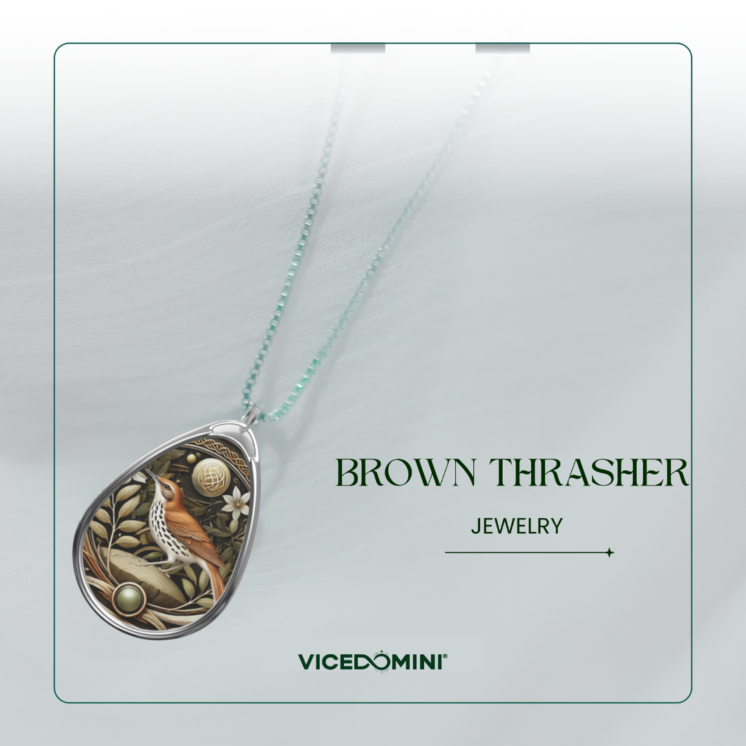 A teardrop-shaped pendant necklace with a detailed brown and beige animal-and-plant illustration, suspended from a pale mint chain on a light gray background. The text 'BROWN THRASHER JEWELRY' and the brand 'VICEDOMINI' appear on the right.