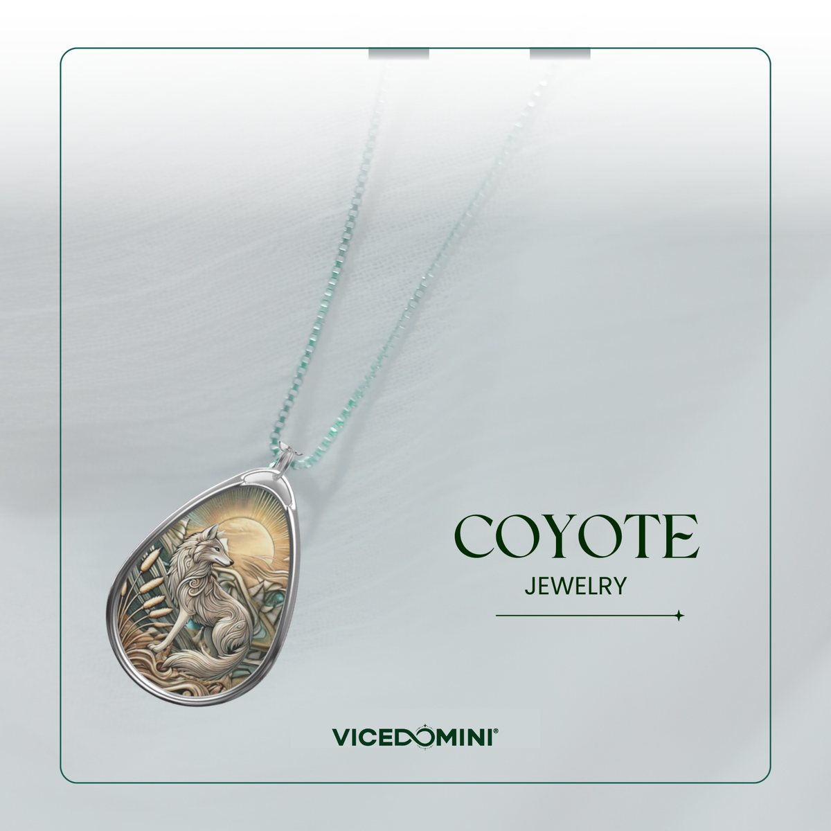 A teardrop-shaped pendant necklace from Vicedomini's Coyote Jewelry collection, featuring a detailed silver-toned coyote and wolf design with a warm gold-toned sunburst background, suspended on a delicate mint-green chain against a light gray textured backdrop.