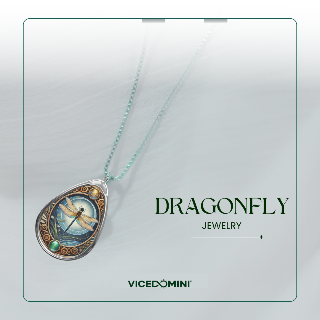 A teardrop-shaped pendant necklace from Vicedomini Dragonfly Jewelry, featuring a detailed dragonfly illustration on a blue background with gold and silver accents, hanging on a delicate mint green chain against a light gray background.