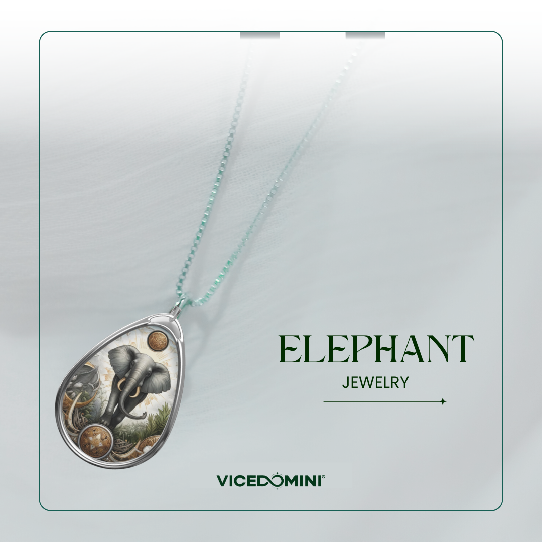 Teardrop-shaped pendant necklace featuring an elephant illustration in silver and gold tones, suspended from a light aqua chain on a white display card with the text 'ELEPHANT JEWELRY' and 'VICEDOMINI'.
