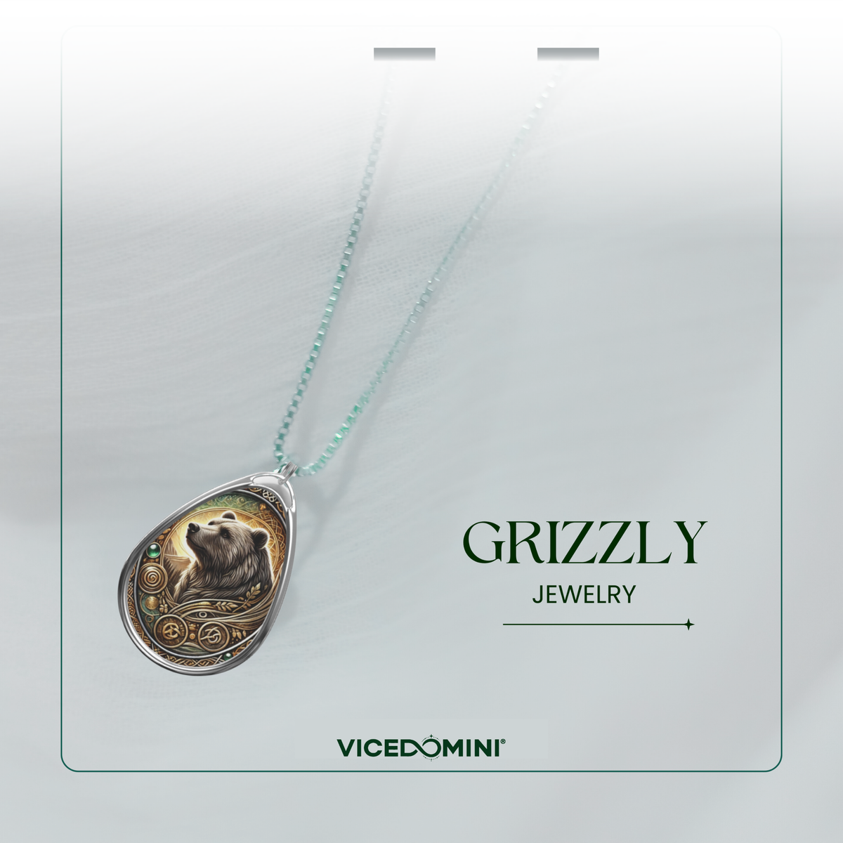 A teardrop-shaped pendant necklace featuring a detailed grizzly bear illustration with gold-toned circular patterns, suspended from a delicate mint-green chain. The necklace is presented on a light gray display card with the text 'GRIZZLY JEWELRY' and the brand 'VICEDOMINI' printed below.