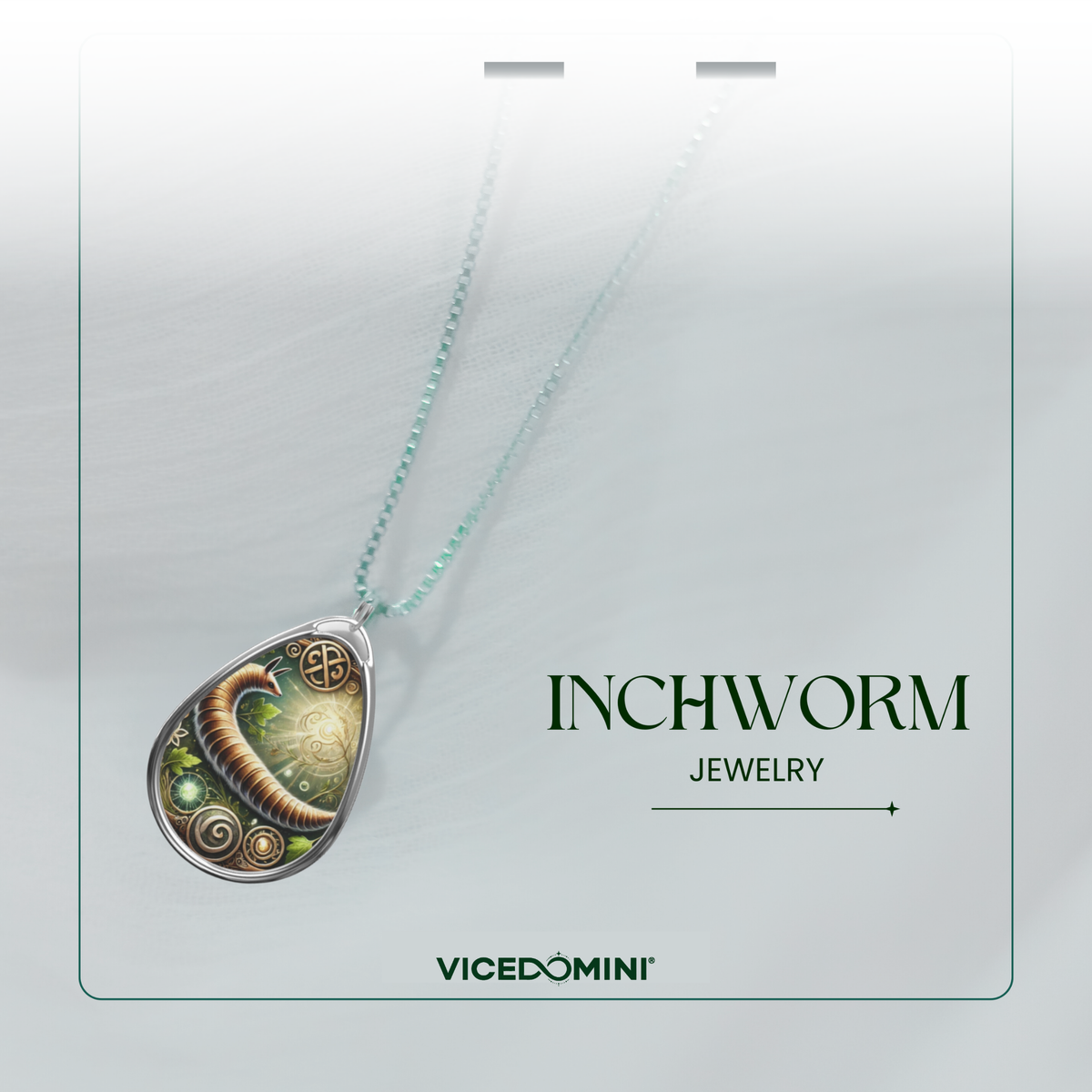 A teardrop-shaped pendant necklace on a matching chain, displayed against a soft light gray background. The pendant features a silver-toned border and a detailed illustration of a green and gold worm with spiral patterns.