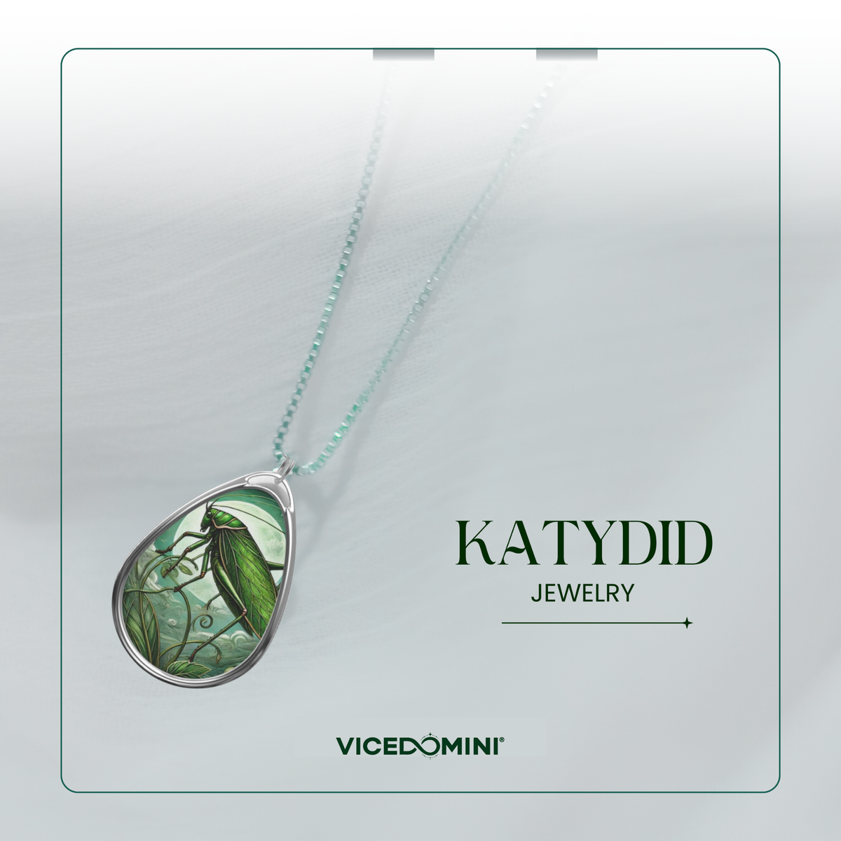 A Katydid Jewelry brand display card featuring a teardrop-shaped pendant necklace with a green and black illustrated insect design set in silver, suspended on a light mint chain. The card has a clean white background with a thin teal border and displays the text 'KATYDID JEWELRY' and 'VICEDOMINI'.