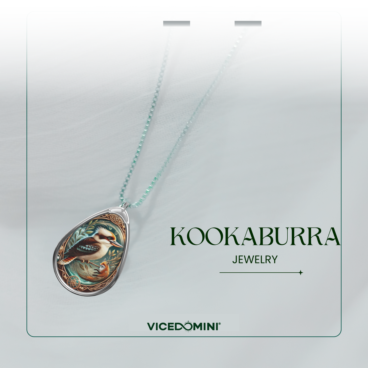 A teardrop-shaped pendant necklace on a fine chain, featuring a detailed kookaburra illustration with turquoise, green, orange, and brown tones in a silver-toned setting. The necklace is displayed on a light gray card with the text 'KOOKABURRA JEWELRY' and the brand 'VICEDOMINI'.