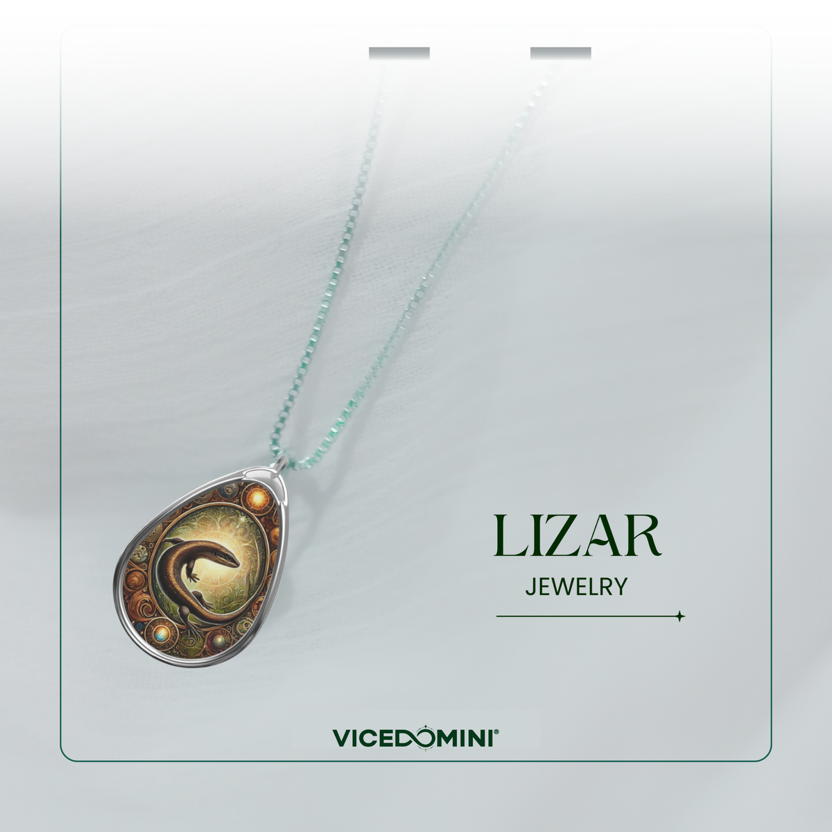 A teardrop-shaped pendant necklace with a silver-toned frame and a detailed fantasy illustration of a dark bird on a gold background, hanging from a light aqua chain. The necklace is presented on a white display card with the text 'LIZAR JEWELRY' and the brand 'VICEDOMINI'.