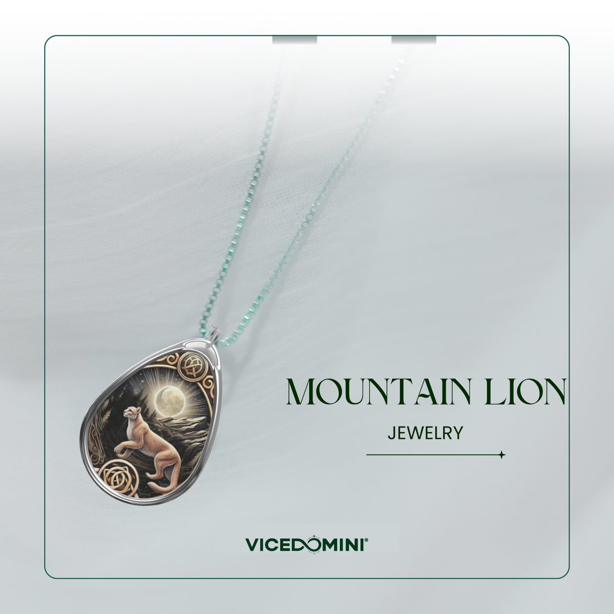 A teardrop-shaped pendant necklace featuring a mountain lion illustration on a dark background with gold circular details, suspended from a light aqua chain. The pendant is displayed on a light gray card with the text 'MOUNTAIN LION JEWELRY' and the brand 'VICEDOMINI'.