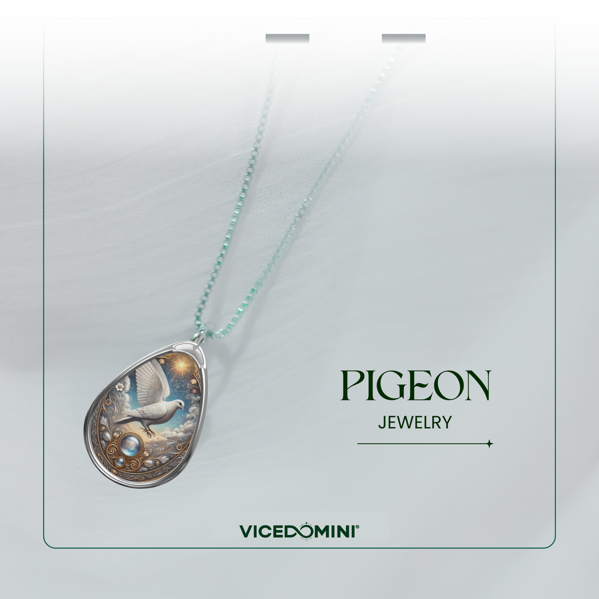 A teardrop-shaped pendant necklace from Vicedomini Pigeon Jewelry, featuring a detailed silver-toned pigeon illustration with blue and gold accents, suspended on a delicate light green chain against a soft white background.