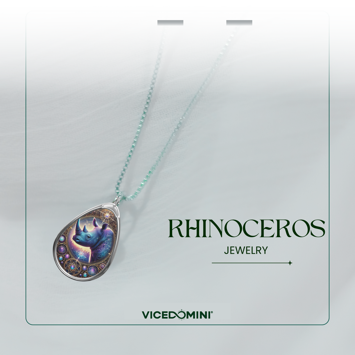 A silver rhinoceros pendant necklace with an ethereal purple and blue design, displayed against a soft white fabric background. The chain is beaded with a subtle gradient, and "Rhinoceros Jewelry" along with the logo VICEDOMINI is elegantly placed in the design.