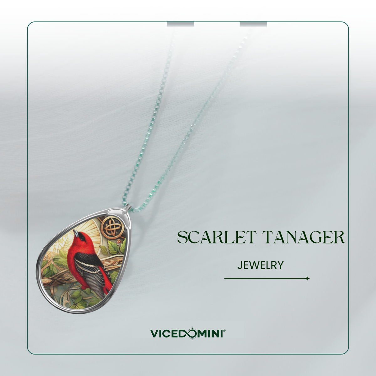 A teardrop-shaped pendant necklace featuring a detailed illustration of a scarlet tanager bird, suspended from a delicate mint green chain. The pendant is displayed on a light gray textured card with branding for 'VICEDOMINI' and the text 'SCARLET TANAGER JEWELRY'.