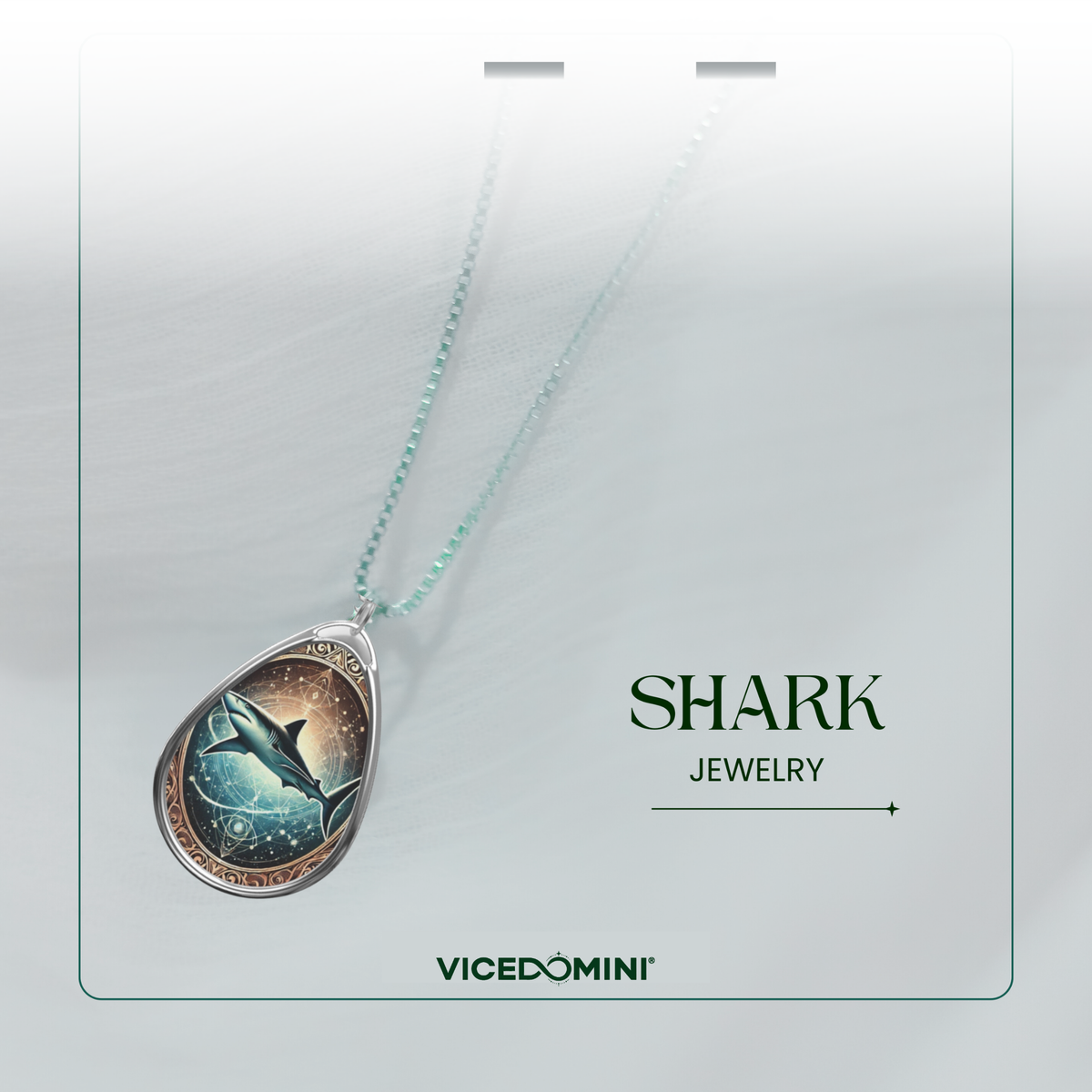 A dreamy close-up of a silver shark pendant necklace draped over a soft, white fabric. The pendant has a celestial design with a shark swimming in a mystical ocean, adorned with glowing star-like details. "SHARK JEWELRY" and "VICEDOMINI" are displayed in the bottom corners.
