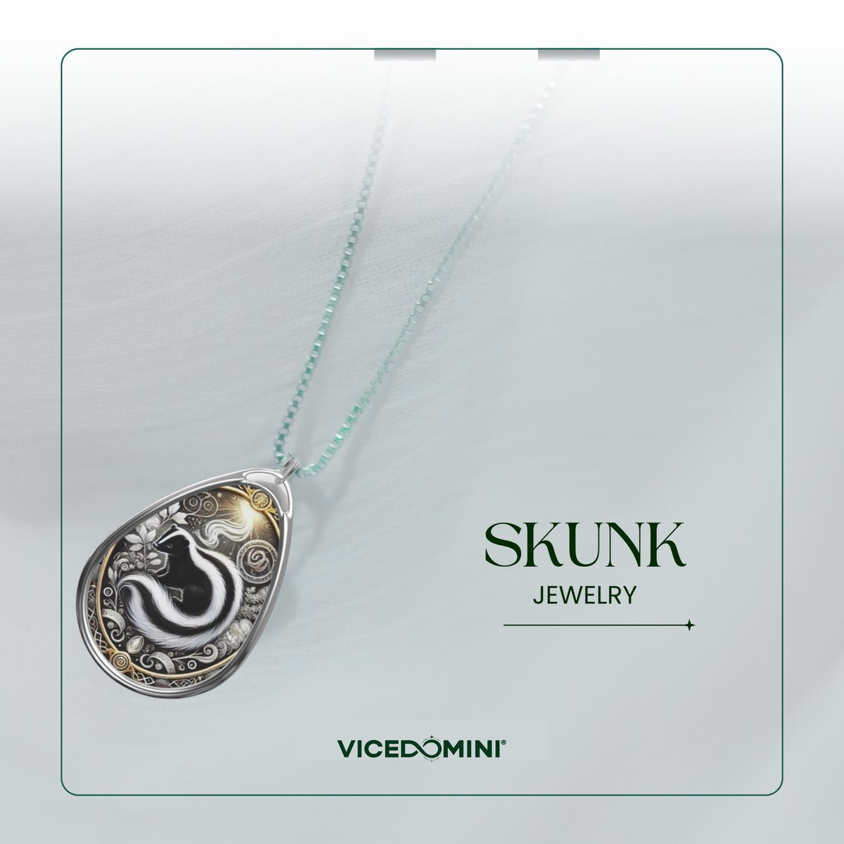A teardrop-shaped silver pendant necklace with a black and white snake design and gold accents, hanging on a delicate mint green chain against a light gray background. The brand name 'SKUNK JEWELRY' is displayed on the right, along with the 'VICEDOMINI' logo.