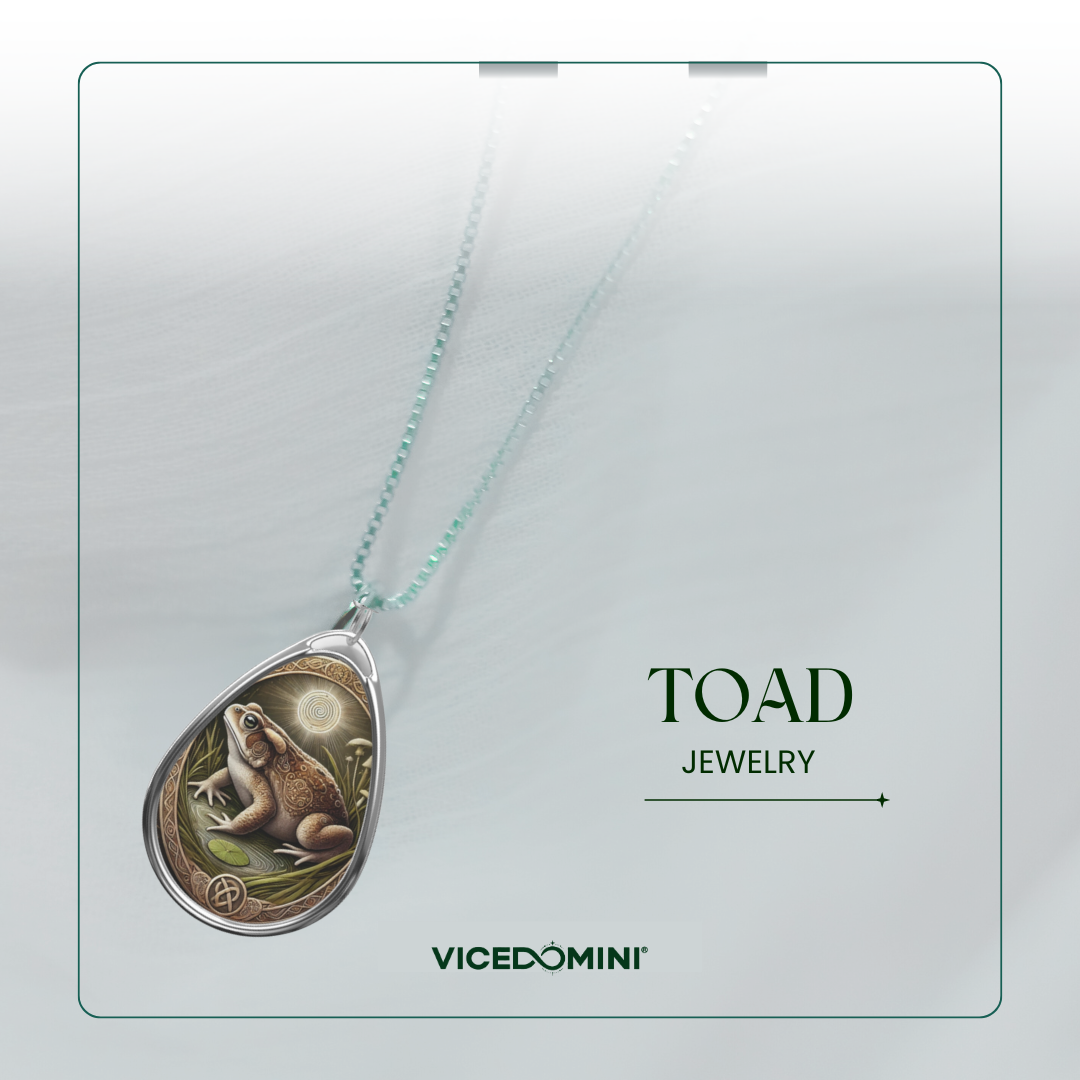 A teardrop-shaped pendant necklace featuring an illustrated toad in a natural scene, suspended from a delicate mint green chain. The pendant is displayed on a clean, light gray background with a thin border, alongside the text 'TOAD JEWELRY' and the brand name 'VICEDOMINI'.