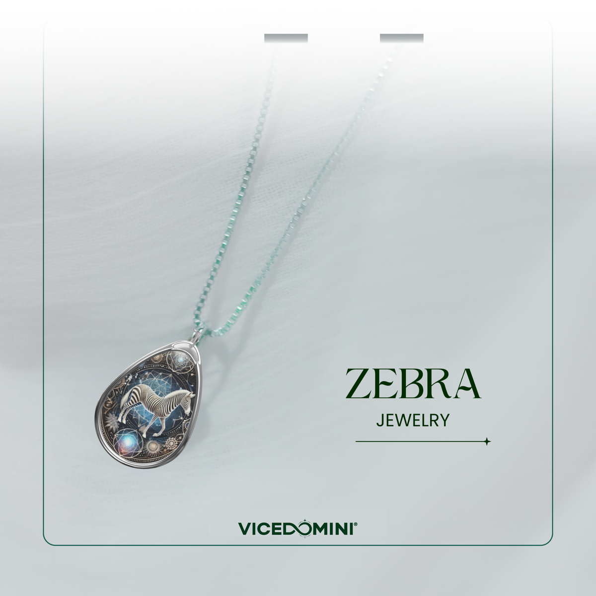 A teardrop-shaped pendant necklace from Vicedomini Zebra Jewelry, featuring a zebra illustration on a starry night sky background with a light blue bead chain, presented on a white display card.