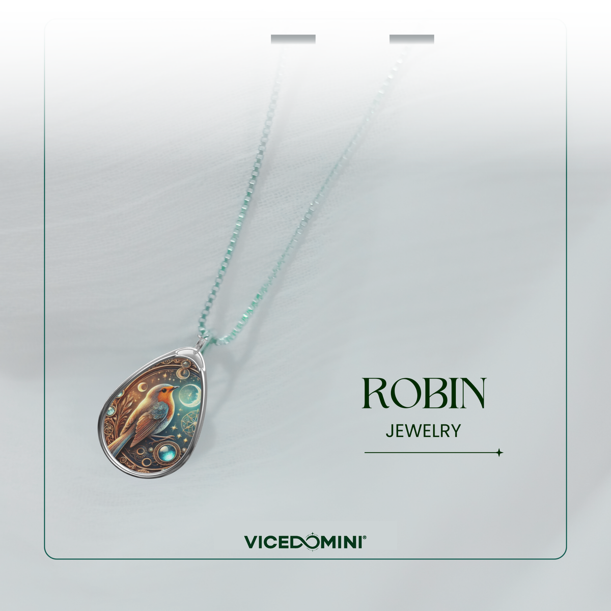 A close-up of the robin necklace pendant hanging from a delicate silver chain, set against a soft white fabric backdrop. The pendant design includes a robin, intricate celestial details, and a glowing gemstone. The text "ROBIN JEWELRY" and "VICEDOMINI" is placed nearby.
