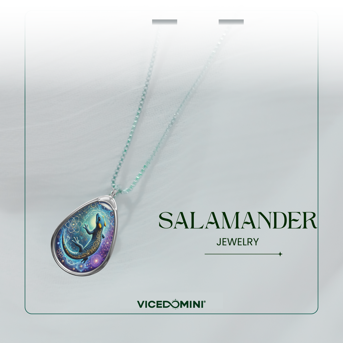 A refined presentation of a silver-chain necklace with a detailed teardrop pendant showcasing a mystical salamander design. The background is soft and blurred, featuring the text "SALAMANDER JEWELRY" and "VICEDOMINI."