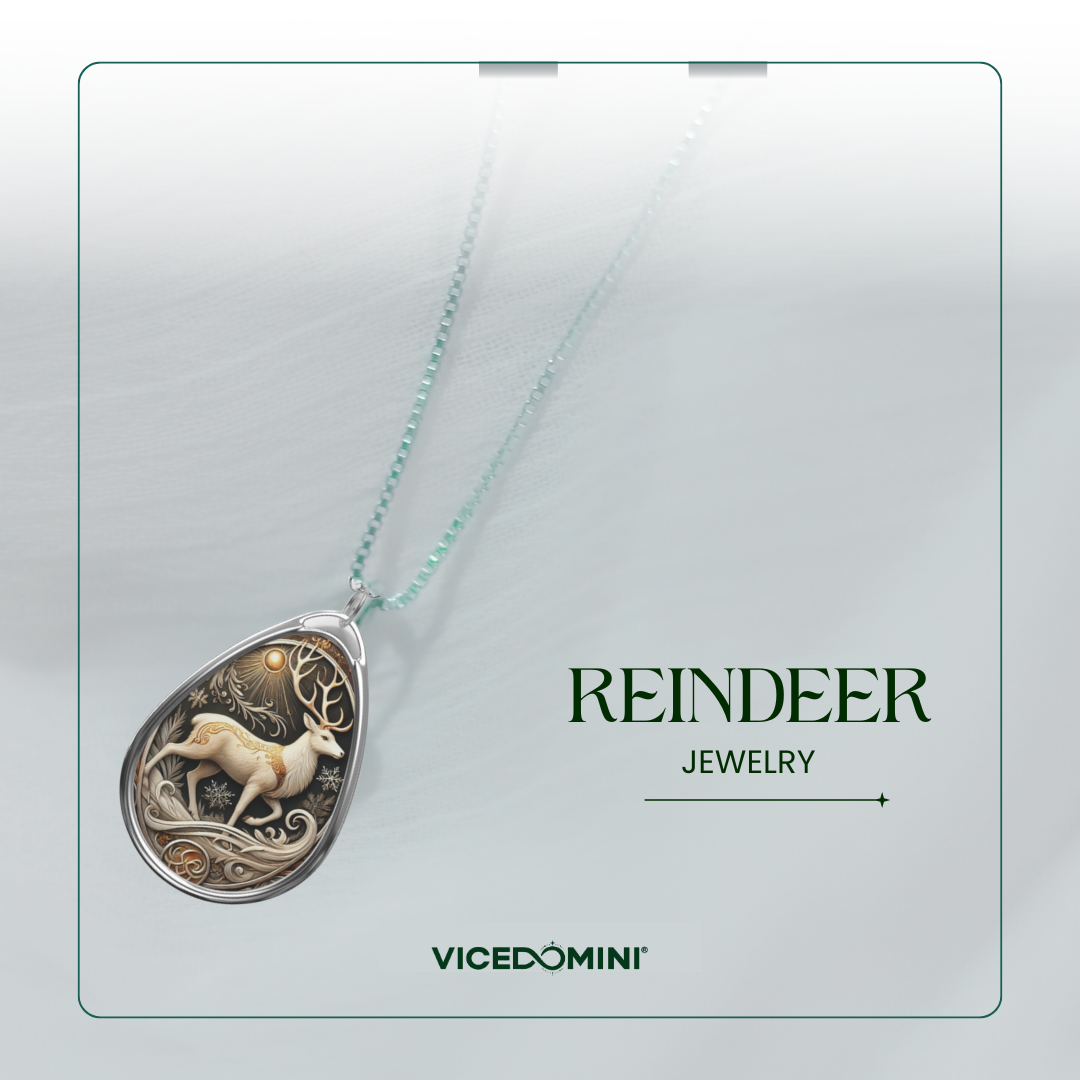 A teardrop-shaped pendant necklace featuring an intricate reindeer and tree design in silver and cream tones, suspended from a light aqua chain. The image is presented on a light gray card with the text 'REINDEER JEWELRY' and the brand 'VICEDOMINI'.